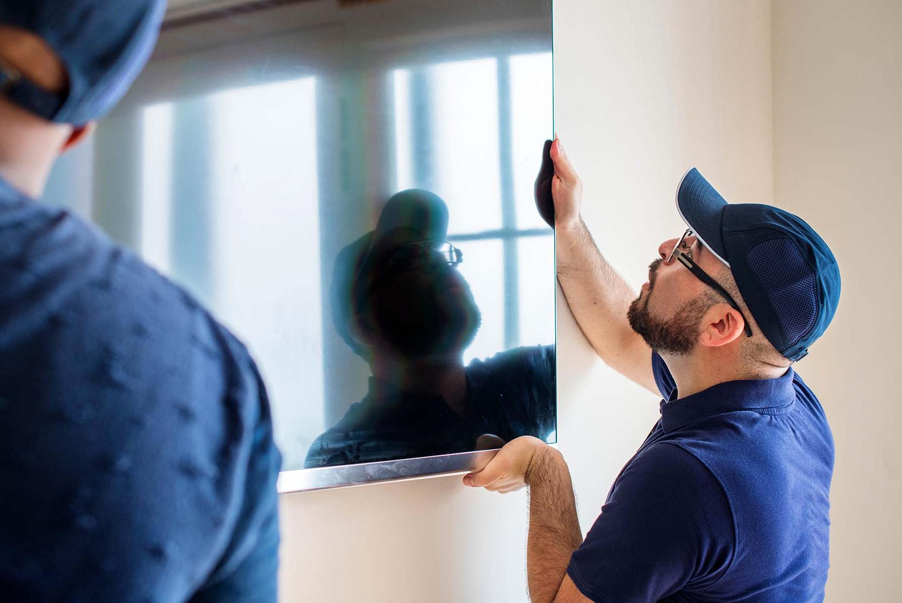 Man installing a TV on a wall.